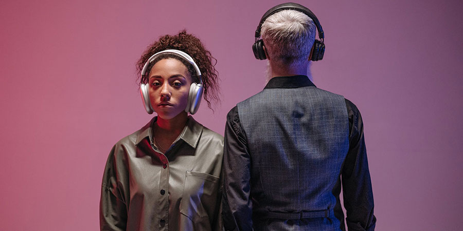 two people wearing headphones with purple gradient background